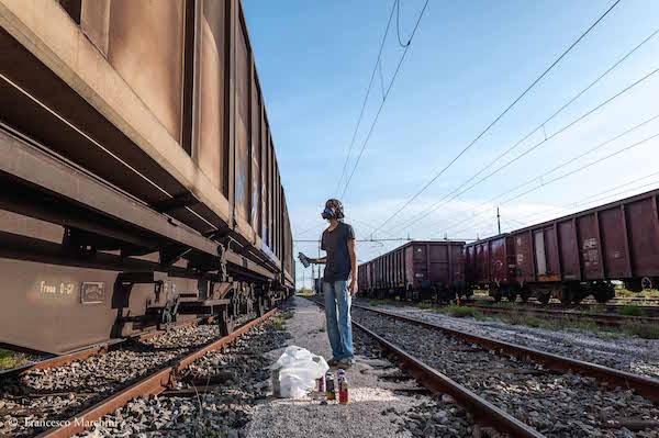 WAOS controlla i colori prima di iniziare a disegnare in un deposito di treni merci abbandonati fuori Roma, 2014
