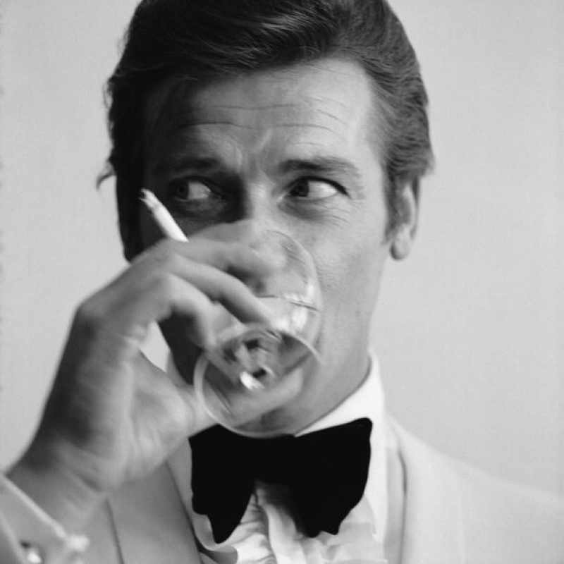 17th July 1968: English film star Roger Moore, well known for his roles as James Bond and the Saint, downs a martini. (Photo by Peter Ruck/BIPs/Getty Images)